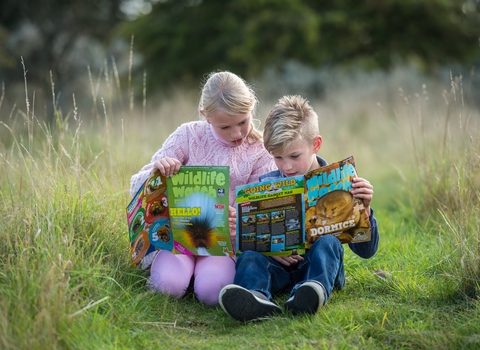 Children comparing notes from their Wildlife Watch magazines, outdoors at Gibraltar Point in Lincolnshire