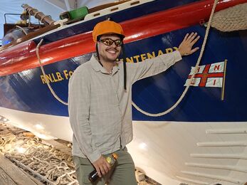 Marine intern George stood in front of a lifeboat