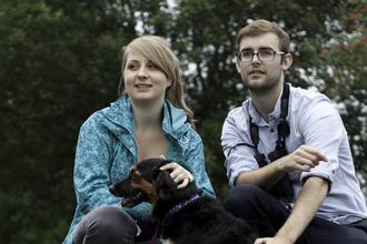 Young couple nature watching with a dog in heathland, August