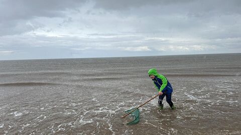 young boy sea dipping on cloudy day
