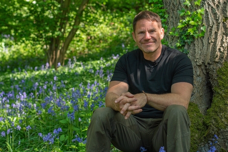 Steve Backshall sitting in a bluebell wood